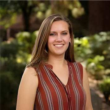 Headshot of Dr. Amanda Rupiper wearing a rust-colored blouse, smiling against a green outdoorsy background.